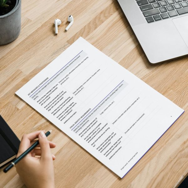 Branding project brief template for freelancers, studios and small businesses by Project Syntax Solutions shown on a desk