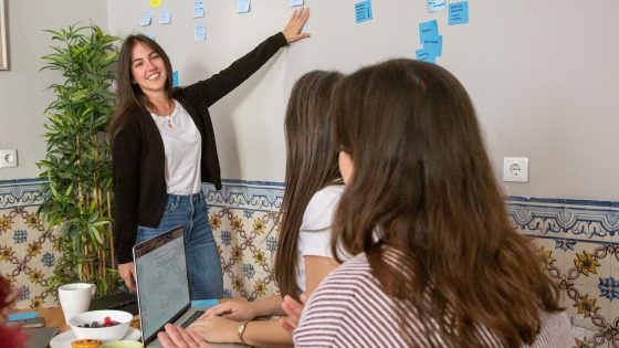 A team collaborating in an Agile planning session with sticky notes on the wall, a laptop, and snacks on the table